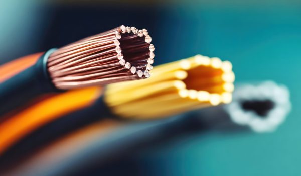 The image shows a close-up view of electrical wires in a workshop. Three wires with exposed copper, yellow, and black strands are displayed, highlighting their structural details and craftsmanship.